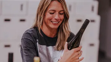 Woman smiling holding a wine bottle indoors.