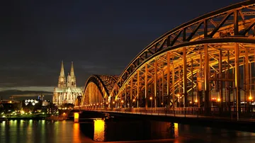 Brücke und beleuchtete Kathedrale bei Nacht.