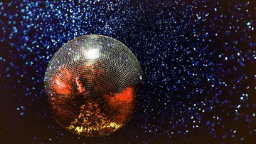 Discokugel reflektiert Licht im dunklen Hintergrund.