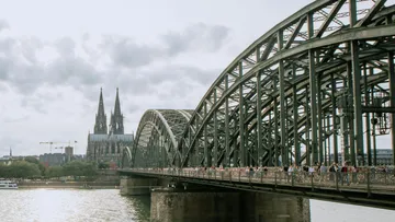 Bridge spanning river with distant cathedral.