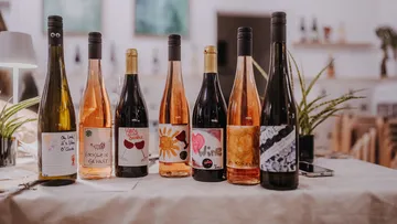 Six wine bottles with unique labels on table.