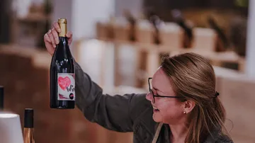 Woman holding wine bottle in shop setting.