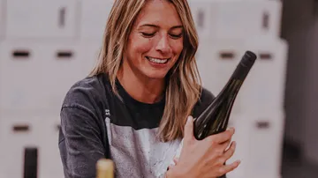 Woman smiling, holding wine bottle indoors.