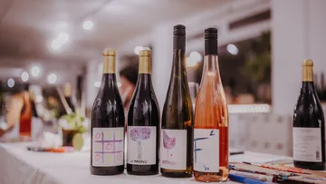 Four wine bottles on a table indoors.