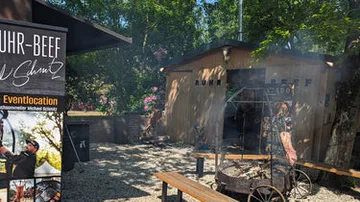 Outdoor grilling area with seating and banner.
