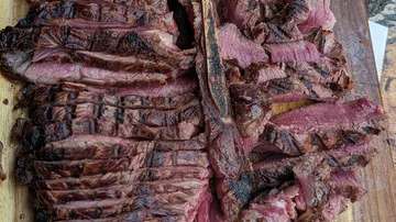 Sliced grilled steak on a wooden board.