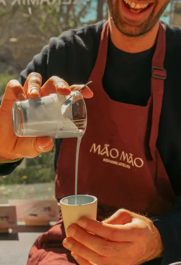 Person pours liquid into cup indoors.