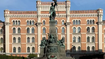 Statue in front of historic building, daylight.