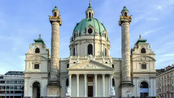 Barockkirche mit grünen Kuppeln, klarer Himmel.