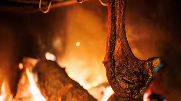 Hanging meat roasting over open fire.