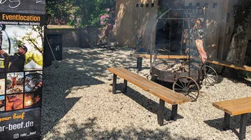 Sitzbänke im Freien, Grill auf Kiesfläche.