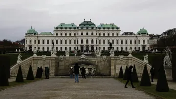 Großes Schloss mit grünem Dach und Statuen, bewölkter Tag.