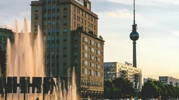 Brunnen und Fernsehturm mit Gebäuden, Sonnenuntergang.