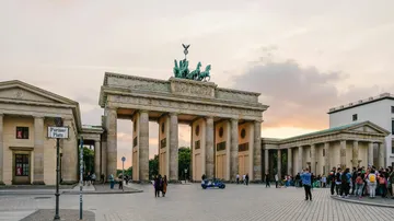 Brandenburger Tor mit Abendhimmel, Menschen drumherum.