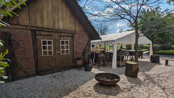 Wooden barn, outdoor seating, sunny weather.
