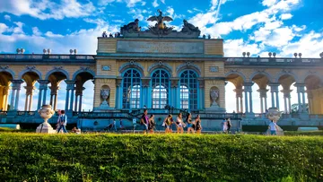 Menschen gehen vor historischem Denkmal.