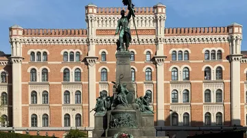 Statue vor verziertem roten Backsteingebäude.