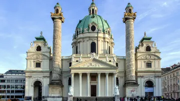 Barockkirche mit Säulen unter blauem Himmel.