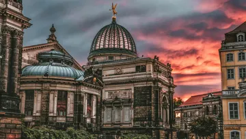 Historisches Gebäude mit Kuppel bei dramatischem Sonnenuntergang.