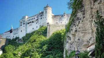 White castle on hill with greenery below.