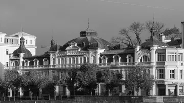 Historic building with domed roof, trees in foreground.