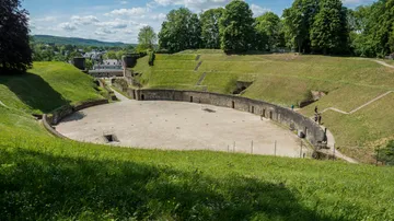 Ancient amphitheater surrounded by grassy hills.