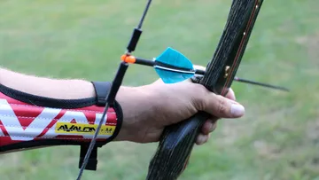Hand hält Bogen mit Pfeil im Freien.