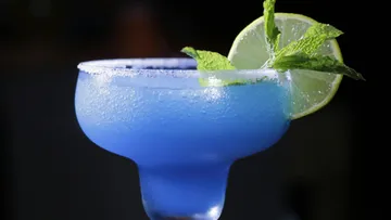 Blauer Cocktail mit Limette und Minze garniert.