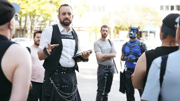 Man speaking to a group outdoors.