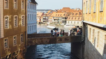 Menschen auf Brücke zwischen historischen Gebäuden.