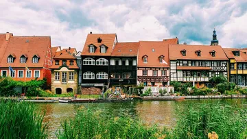 Bunte Häuser an einem Fluss unter Wolkenhimmel.