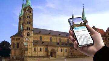 Hand hält Handy, zeigt Kircheninformationen.