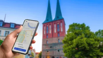 Hand hält Handy mit Karte nahe Kirche.
