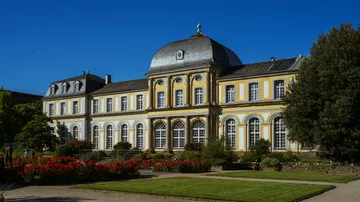 Historisches Gebäude mit Gärten unter klarem Himmel.