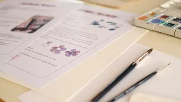 Pinsel und Papier mit Aquarellanleitung.