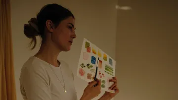 Frau hält farbiges Papier, betrachtet Designs.
