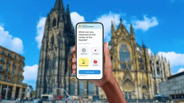 Hand hält Handy vor Kathedrale.