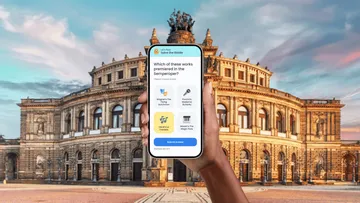 Person holding phone in front of historic building.
