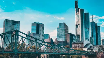 Skyscrapers under clear sky, bridge foreground.