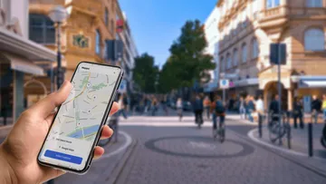 Hand hält Smartphone mit Karte auf belebter Straße.