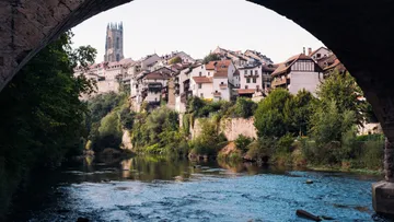 Stadtlandschaft mit Fluss unter Torbogen.