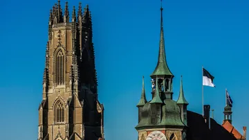Gotische Kathedrale und Uhrturm unter blauem Himmel.