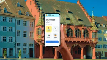 Person hält Smartphone vor historischem Gebäude.