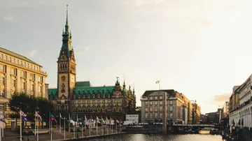 Rathaus am Wasser mit Fahnen, Sonnenuntergang.