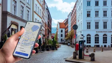Hand hält Handy mit Karte in Stadtstraße.