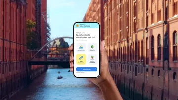 Hand hält Handy in städtischer Kanalumgebung.