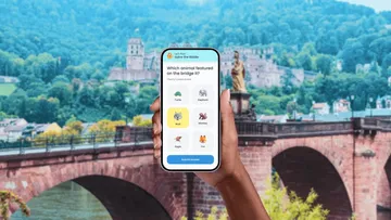 Hand holding phone displaying quiz, bridge background.