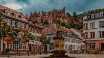 Historic square with statue and castle in background.