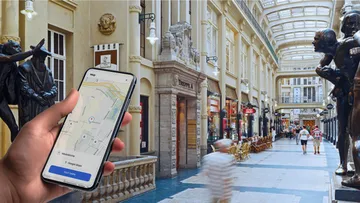 Hand holds phone with map in shopping arcade.