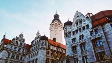 Historischer Turm mit angrenzenden Gebäuden, klarer Himmel.
